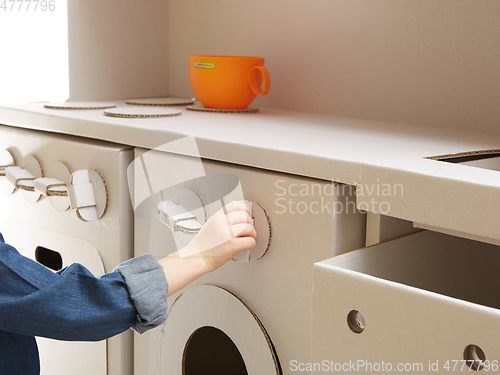 Image of Child girl playing with toy kitchen at home