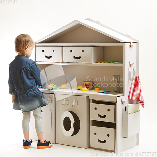 Image of toddler girl playing with toy kitchen at home