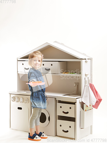 Image of toddler girl playing with toy kitchen at home