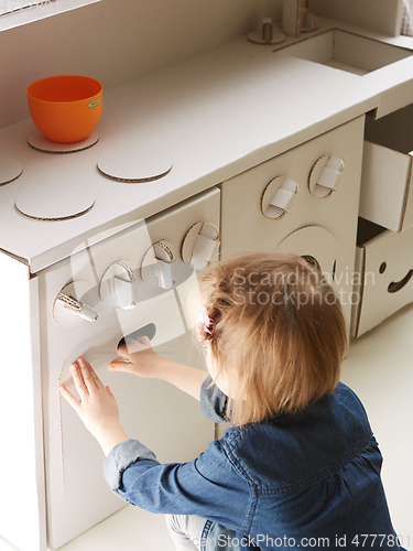 Image of toddler girl playing with toy kitchen at home