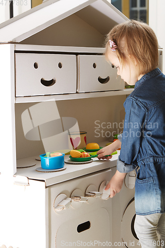 Image of toddler girl playing with toy kitchen at home