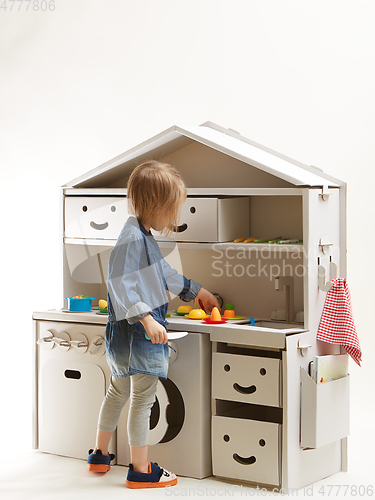 Image of toddler girl playing with toy kitchen at home