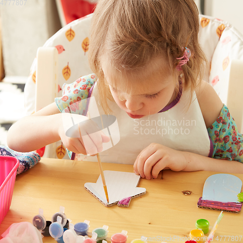 Image of Cute little girl painting on home interior background