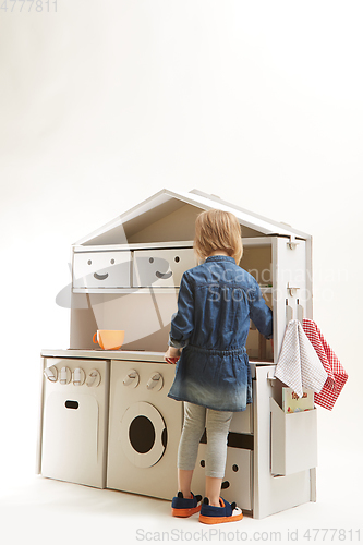 Image of toddler girl playing with toy kitchen at home