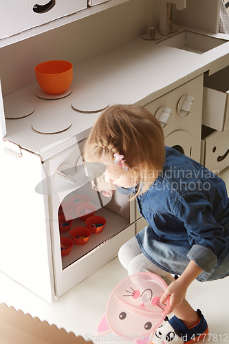 Image of toddler girl playing with toy kitchen at home