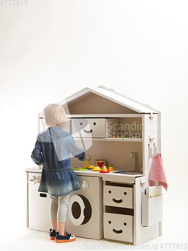 Image of toddler girl playing with toy kitchen at home