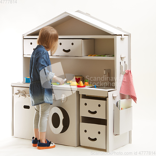 Image of toddler girl playing with toy kitchen at home