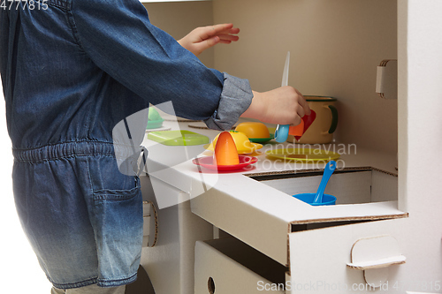 Image of Child girl playing with toy kitchen at home