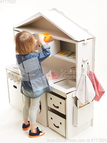 Image of toddler girl playing with toy kitchen at home