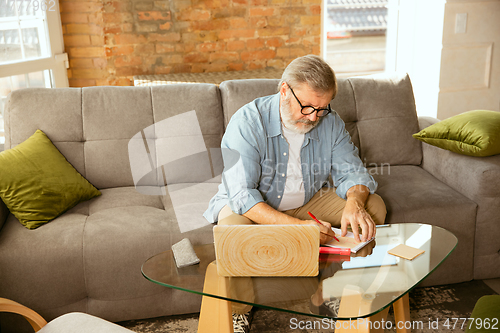Image of Senior man working with laptop at home - concept of home studying