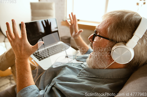 Image of Senior man working with laptop at home - concept of home studying