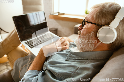 Image of Senior man working with laptop at home - concept of home studying