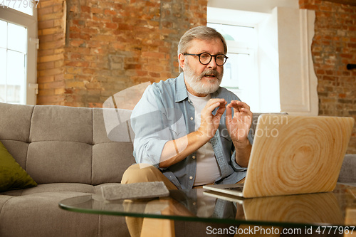 Image of Senior man working with laptop at home - concept of home studying