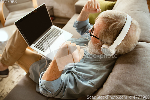 Image of Senior man working with laptop at home - concept of home studying