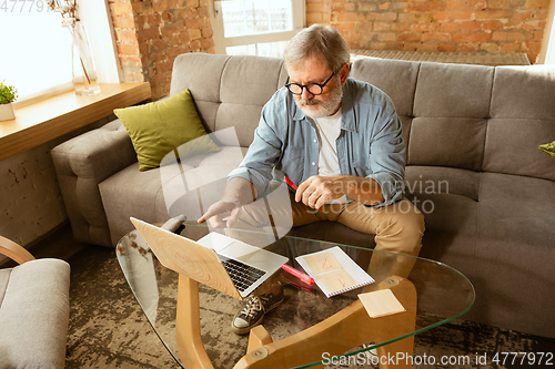 Image of Senior man working with laptop at home - concept of home studying