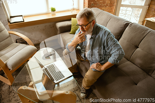 Image of Senior man working with laptop at home - concept of home studying