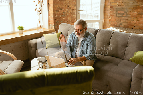 Image of Senior man working with laptop at home - concept of home studying