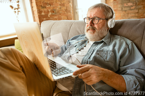 Image of Senior man working with laptop at home - concept of home studying