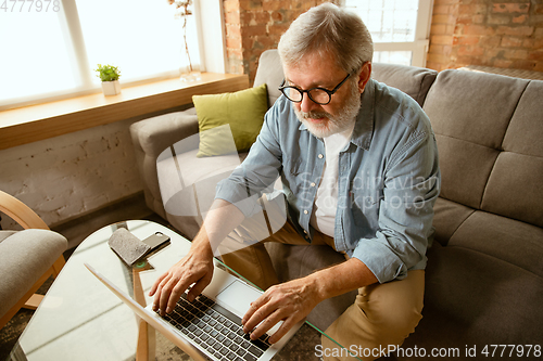 Image of Senior man working with laptop at home - concept of home studying