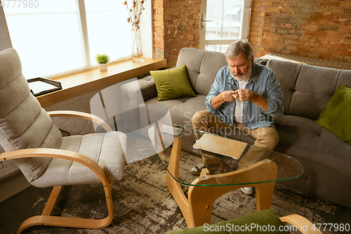 Image of Senior man working with laptop at home - concept of home studying