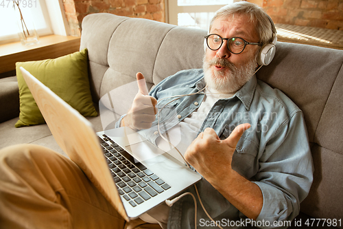 Image of Senior man working with laptop at home - concept of home studying