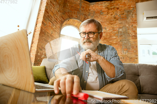 Image of Senior man working with laptop at home - concept of home studying