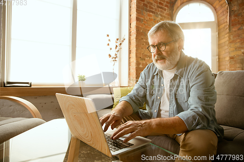 Image of Senior man working with laptop at home - concept of home studying