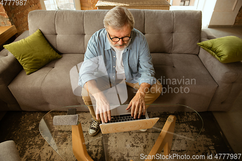 Image of Senior man working with laptop at home - concept of home studying