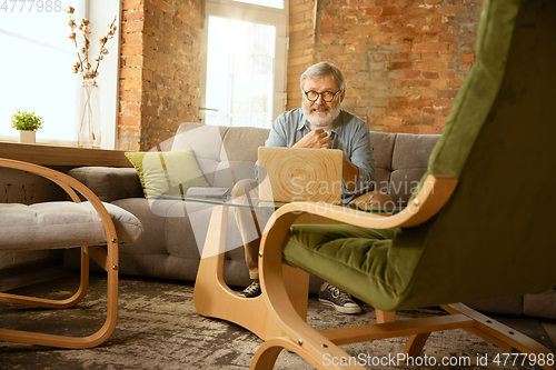 Image of Senior man working with laptop at home - concept of home studying