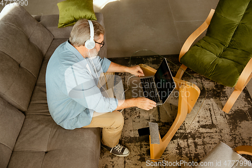 Image of Senior man working with laptop at home - concept of home studying