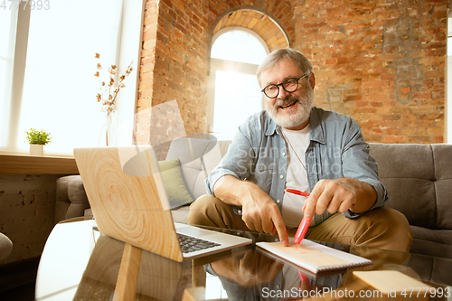 Image of Senior man working with laptop at home - concept of home studying