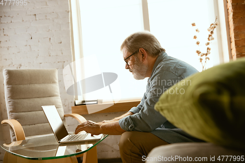 Image of Senior man working with laptop at home - concept of home studying