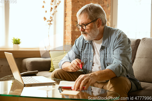 Image of Senior man working with laptop at home - concept of home studying