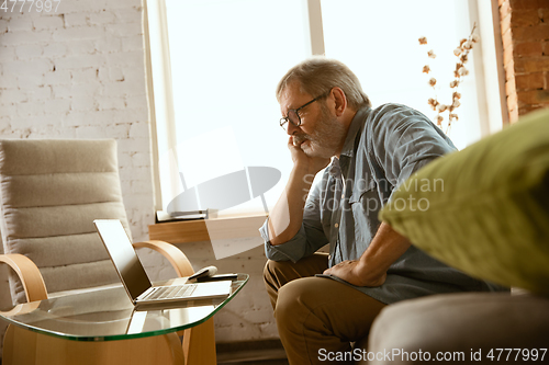 Image of Senior man working with laptop at home - concept of home studying