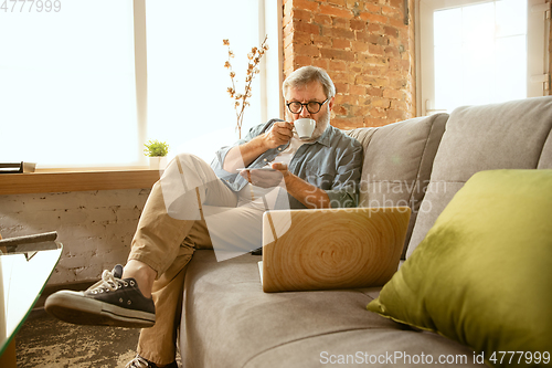 Image of Senior man working with laptop at home - concept of home studying