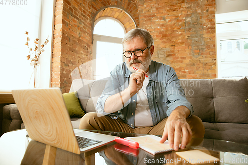 Image of Senior man working with laptop at home - concept of home studying