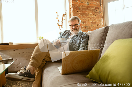 Image of Senior man working with laptop at home - concept of home studying