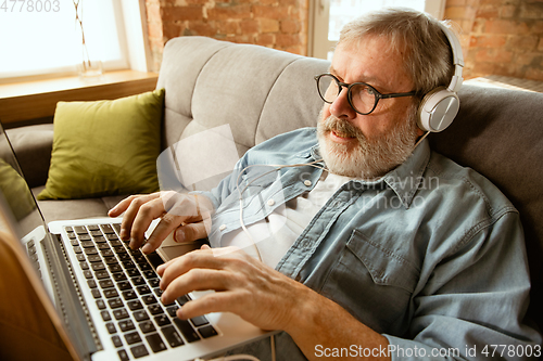 Image of Senior man working with laptop at home - concept of home studying