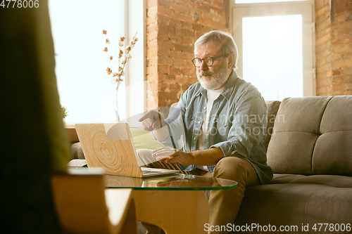 Image of Senior man working with laptop at home - concept of home studying