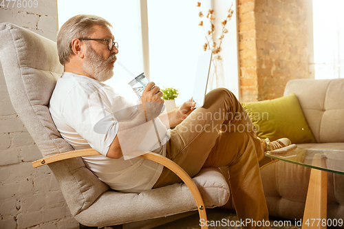 Image of Senior man working with tablet at home - concept of home studying