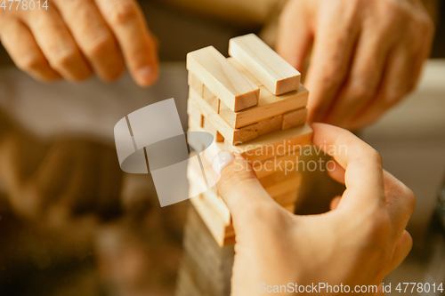 Image of Close up of senior man\'s hands doing his wooden constructor at home - concept of home studying