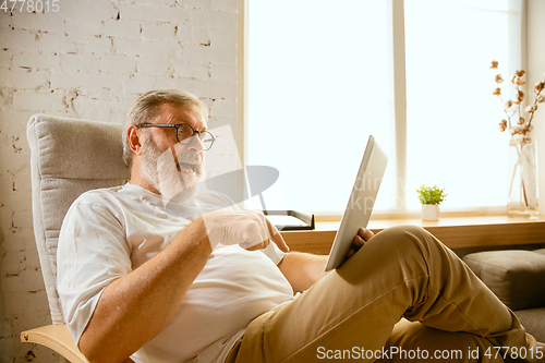 Image of Senior man working with tablet at home - concept of home studying