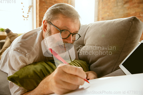 Image of Senior man working with tablet at home - concept of home studying