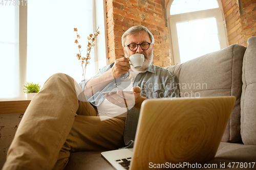 Image of Senior man working with laptop at home - concept of home studying