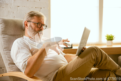 Image of Senior man working with tablet at home - concept of home studying