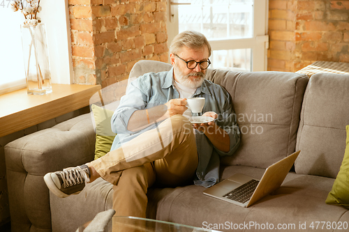 Image of Senior man working with laptop at home - concept of home studying