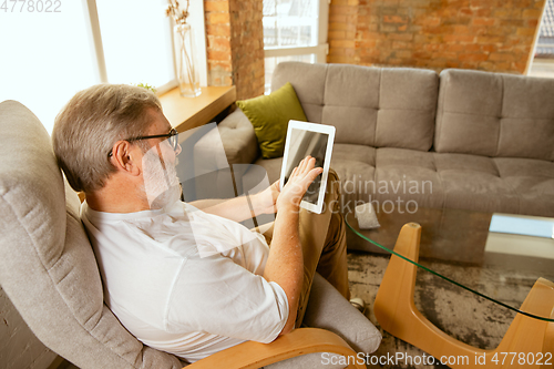 Image of Senior man working with tablet at home - concept of home studying