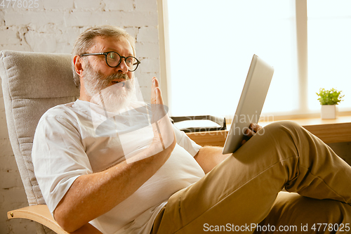 Image of Senior man working with tablet at home - concept of home studying