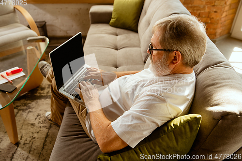 Image of Senior man working with laptop at home - concept of home studying