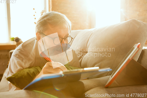 Image of Senior man working with tablet at home - concept of home studying